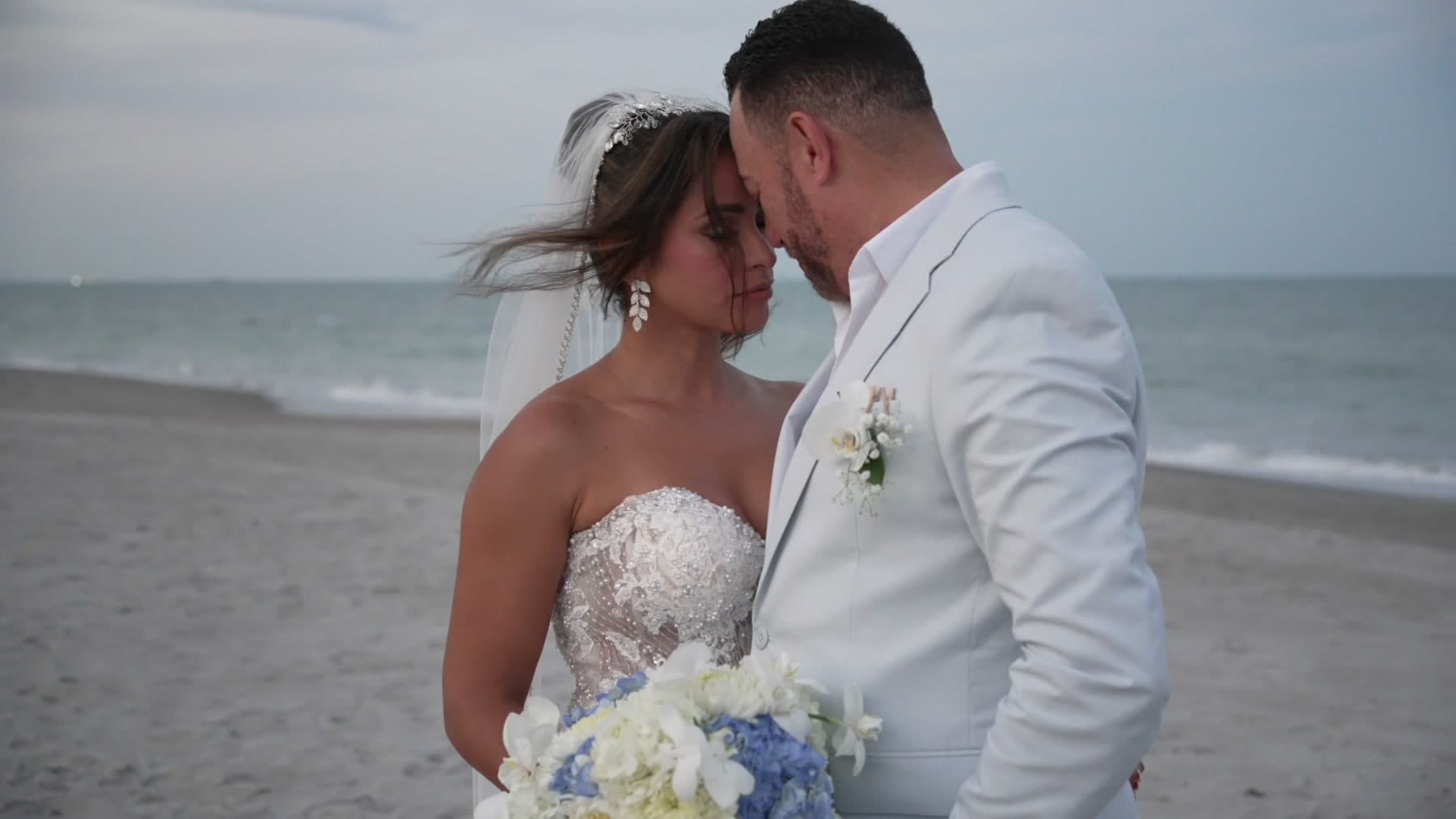 A couple holding each other close beside the ocean
